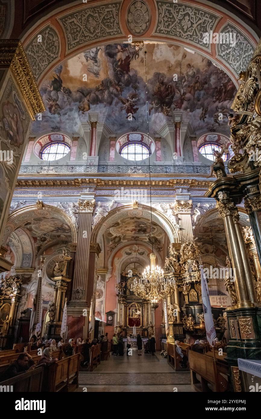 Das Innere einer Kirche mit einer goldenen Decke und goldenen Säulen. Die Kirche ist voller Menschen und die Atmosphäre ist sehr friedlich Stockfoto