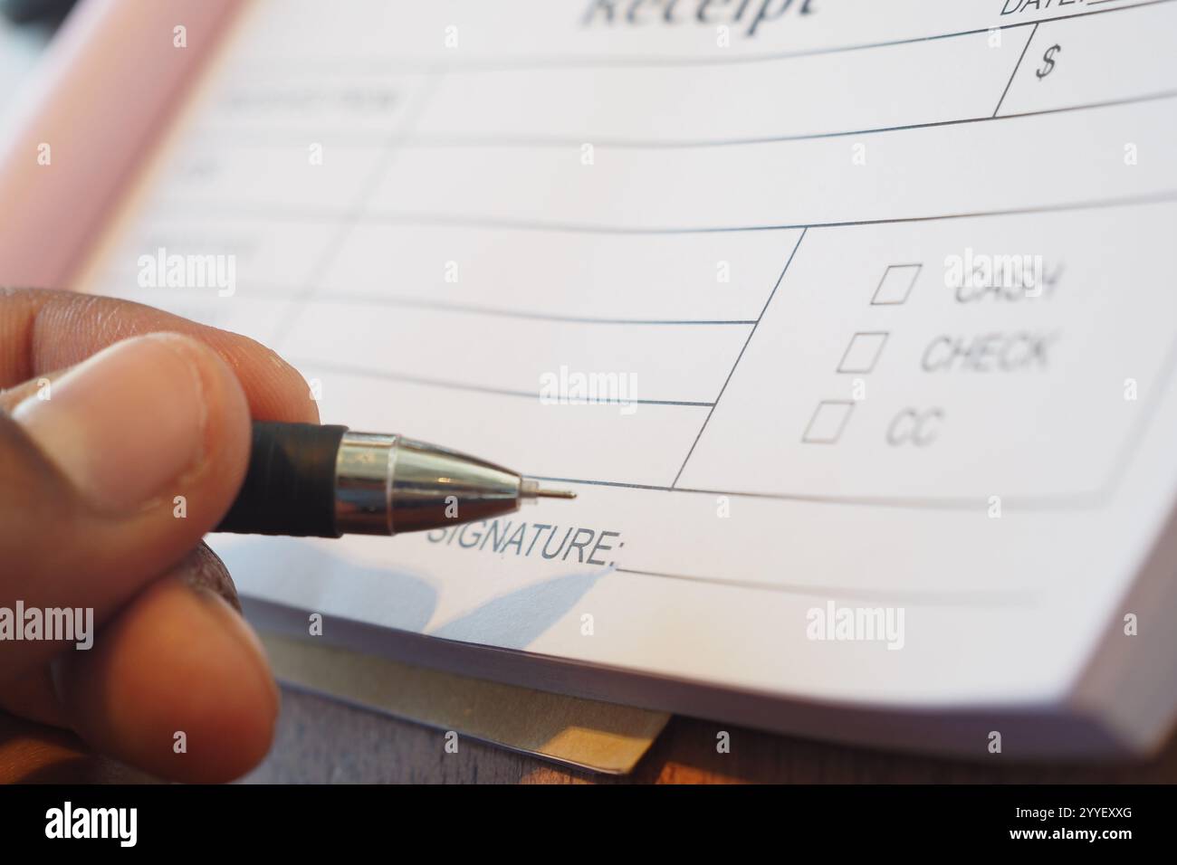Unterzeichnen Sie mit einem Stift auf einem Holztisch eine detaillierte Quittung Stockfoto