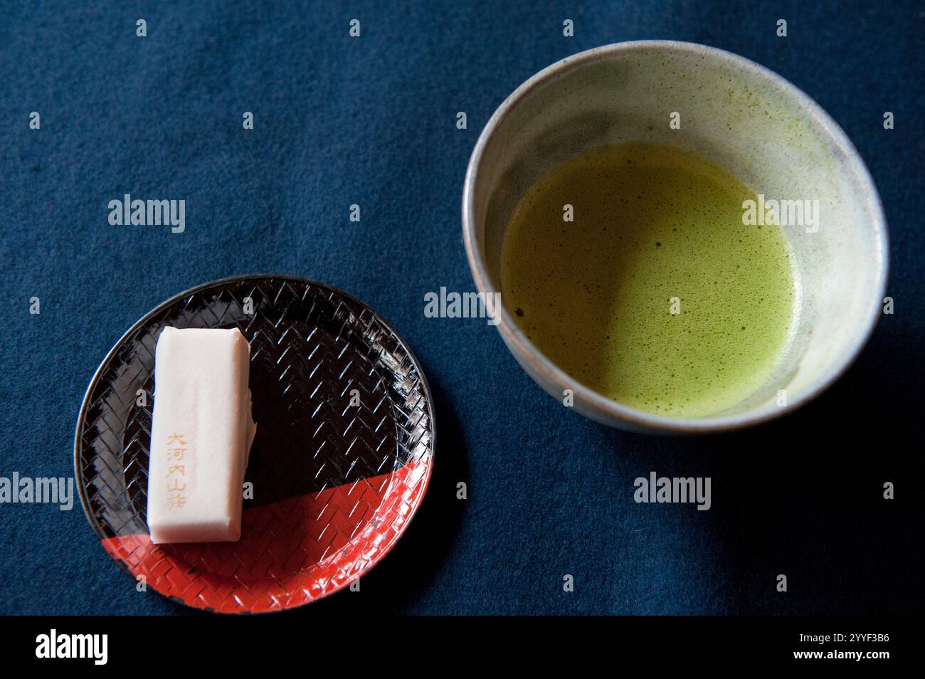 Japanischer aufschäumender Bittertee-Zeremonie Tee namens „Matcha“ wird in einer Porzellanschale serviert, begleitet von einem traditionellen süßen Snack namens „okashi“, Japan. Stockfoto