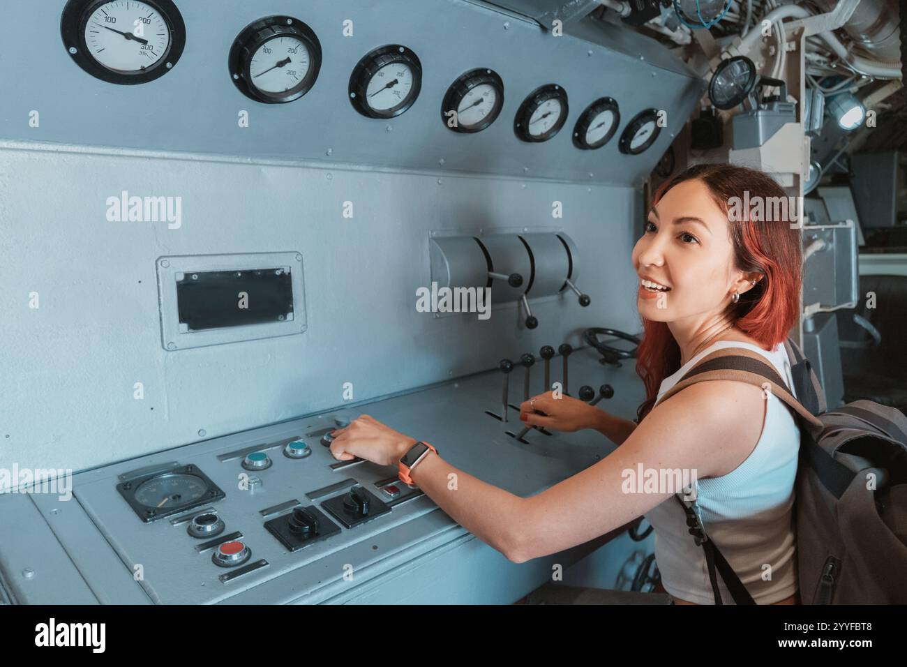 Junge Touristin erkundet das Innere eines U-Bootes, Bedienhebel und Knöpfe im Kontrollraum Stockfoto