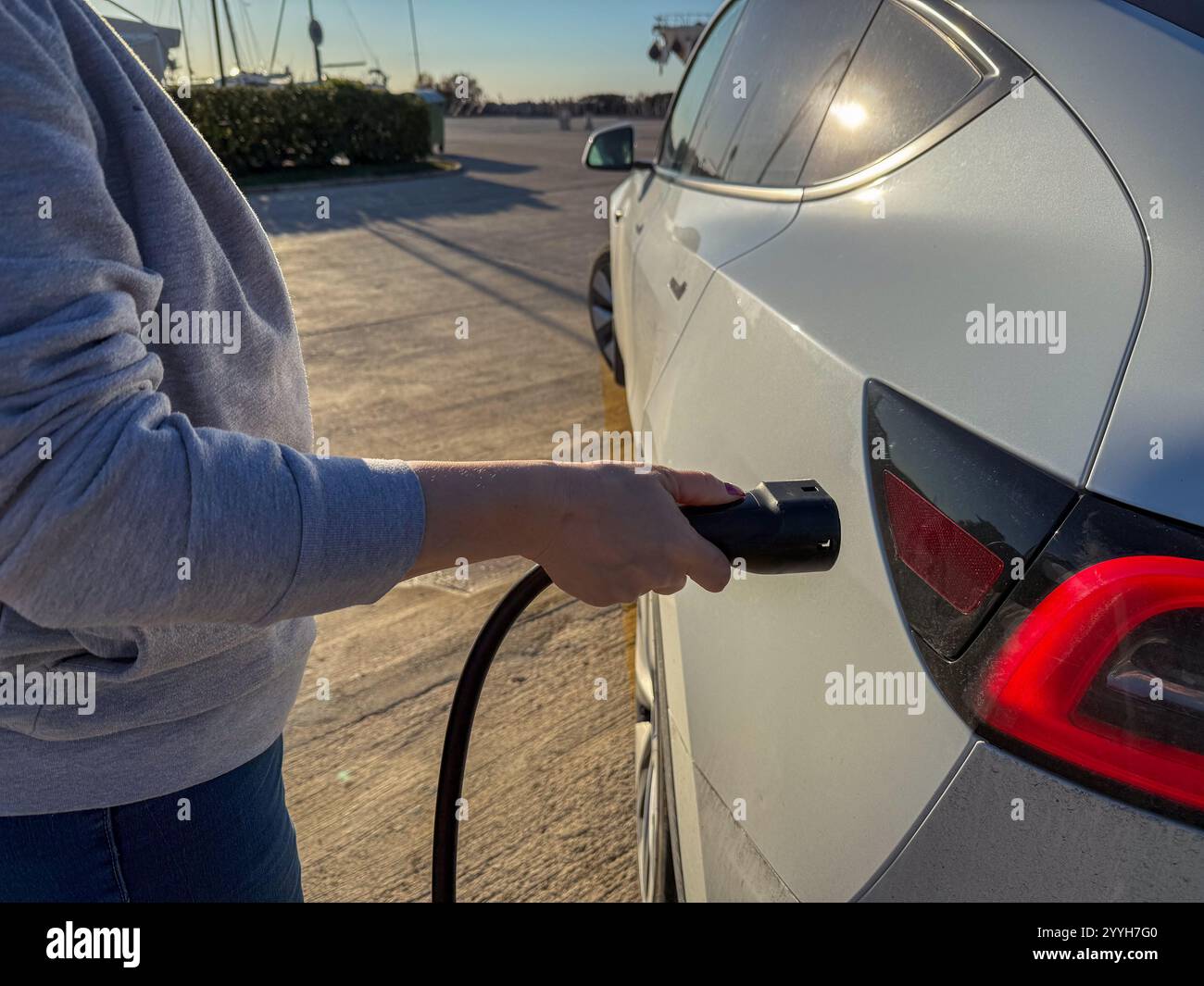 Laden eines Elektrofahrzeugs bei Sonnenlicht am Morgen Stockfoto