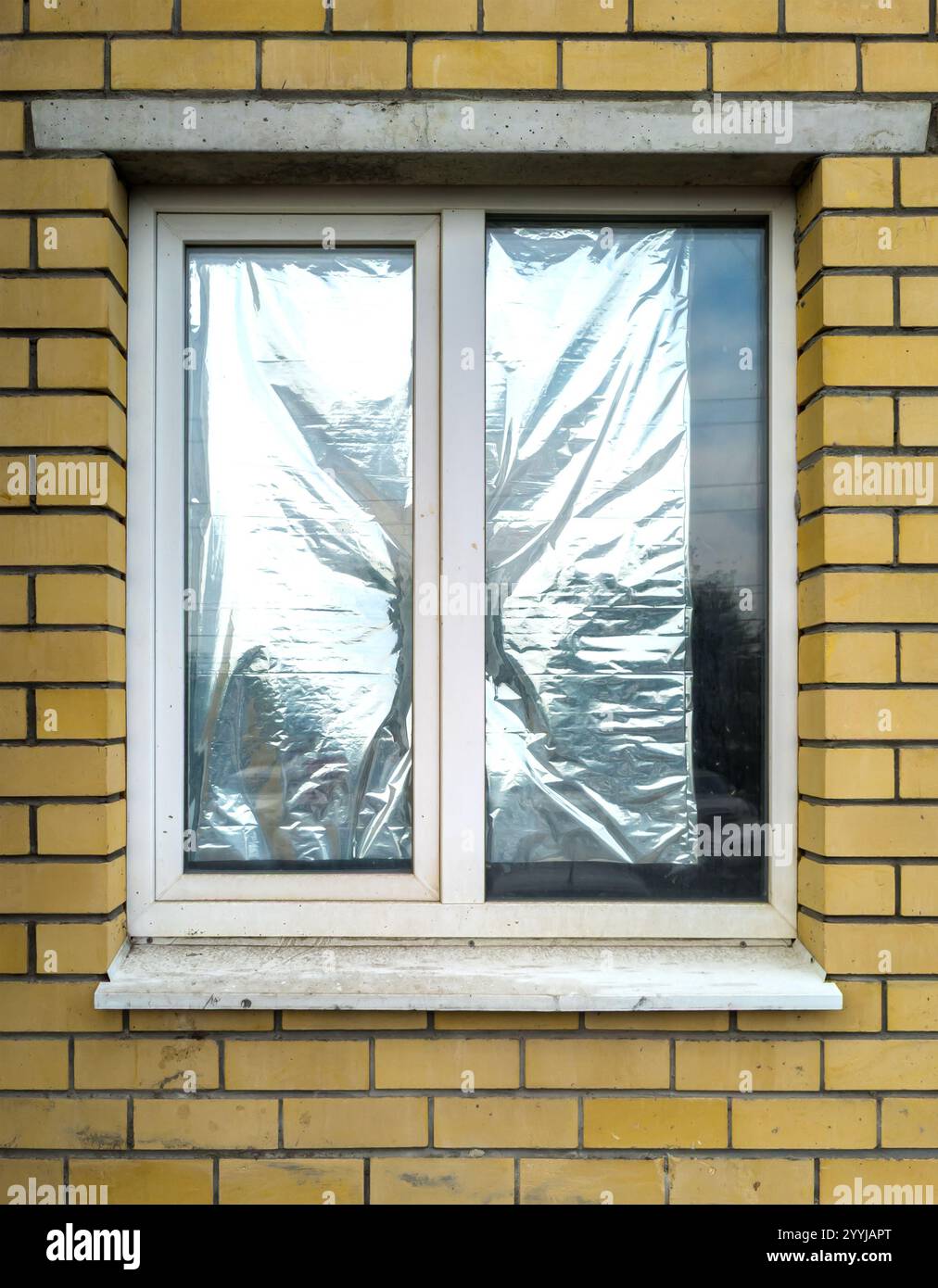 Dünne silberne Polymerfolie am Fenster als Wärmereflektor Stockfoto