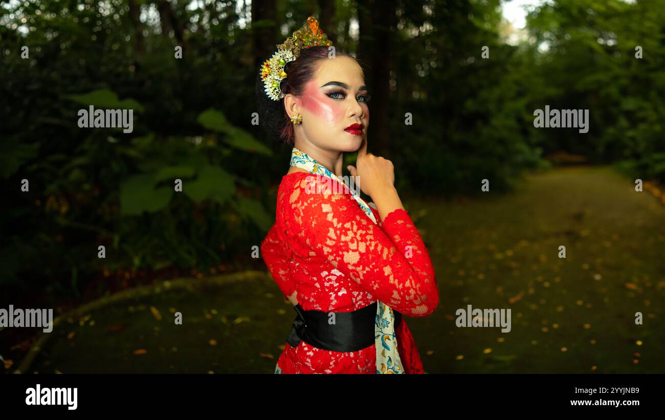 Ein traditioneller Tänzer namens Ronggeng steht mit einem Ausdruck voller Schönheit und Schönheit in einem magischen Wald am Nachmittag Stockfoto