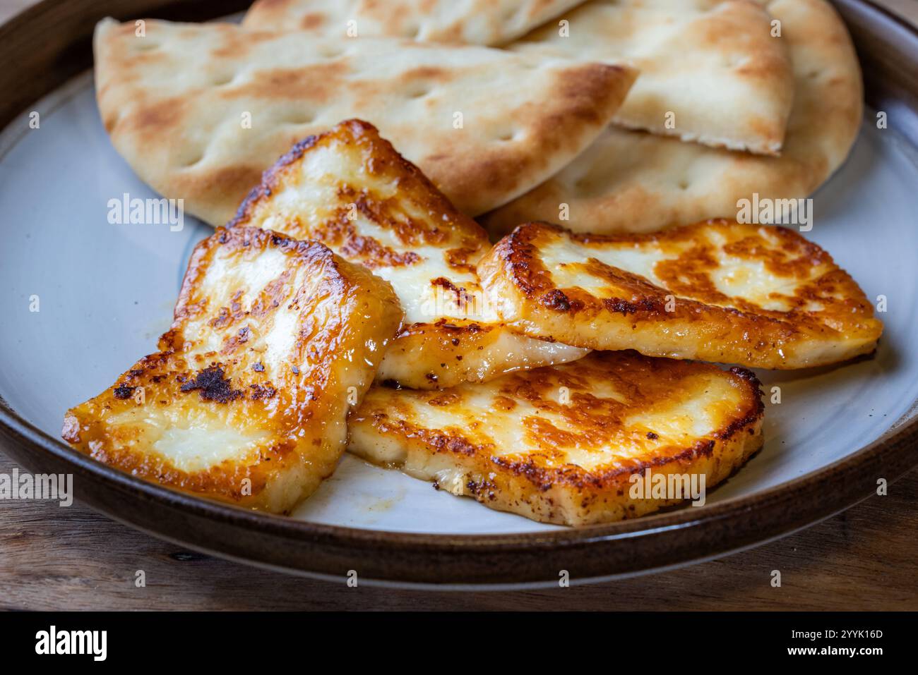 Ein Teller mit gebratenem halloumi-Käse mit einer Seite Pita-Brot. Das Essen ist goldbraun und sieht köstlich aus. Stockfoto