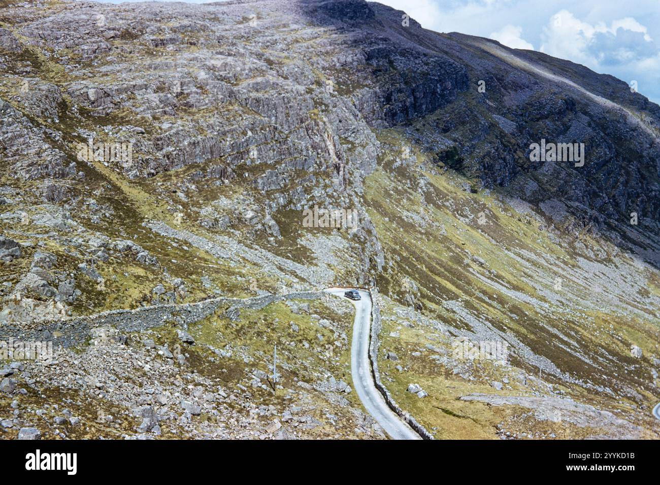 Historisches Foto eines Autos in einer Hiarpin-Kurve auf einer abgelegenen einspurigen Bergstraße in den schottischen Highlands, dem Bealach-na-BA Pass in Schottland, Großbritannien in den 1960er Jahren Stockfoto