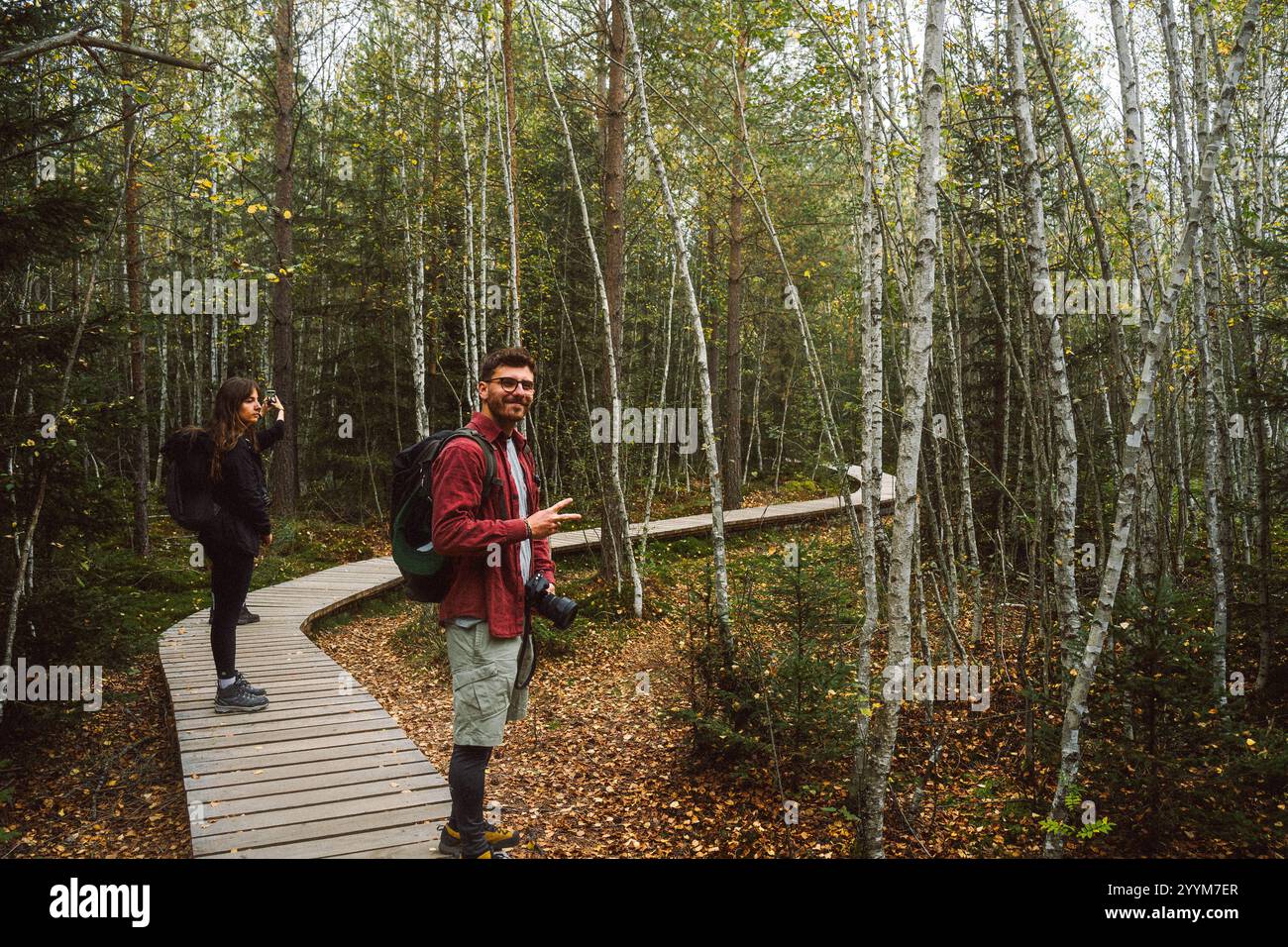 Ein Mann und eine Frau stehen zusammen auf einem rustikalen Holzsteg, der tief in einem üppig grünen Waldgebiet im Wald liegt Stockfoto