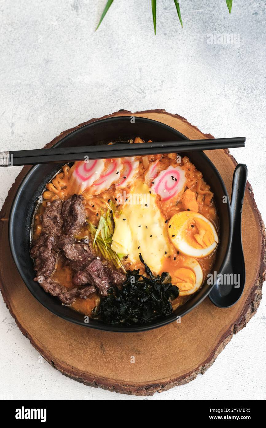 Eine verführerische Ramen-Schüssel gefüllt mit scharfen Nudeln, saftigem Rindfleisch, einem perfekt gekochten Ei und frischem Gemüse Stockfoto