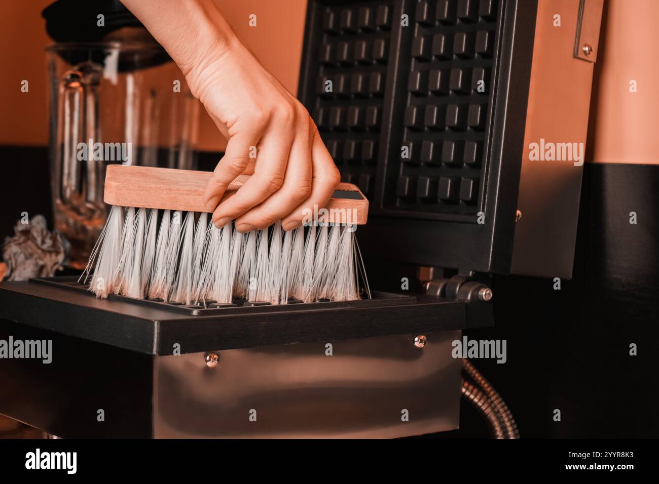 pantone 2025. Schmutzige Waffelmaschine. Schmutzige Waffelmaschine mit verbranntem Teig auf der Oberfläche. Die Arbeitsfläche eines alten elektrischen Waffeleisens. Reinigung Stockfoto