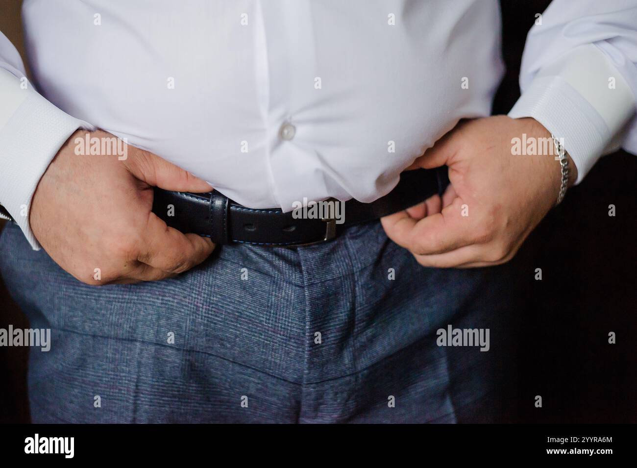 Mann, der seinen Gürtel anpasst, während er ein formelles Outfit trägt. Stockfoto