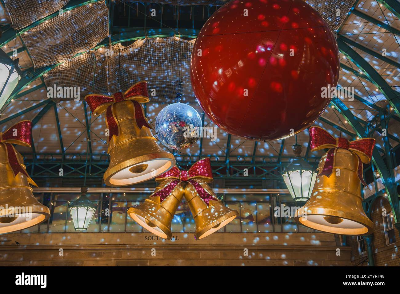 Der Covent Garden Market in London bietet große goldene Glocken, eine riesige rote Kugel und eine Discokugel. Das legendäre grüne Eisen und das Glasdach sind sichtbar. Stockfoto