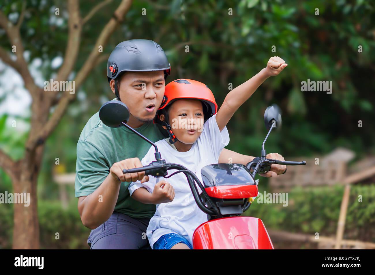 Ein fröhlicher asiatischer Vater und Sohn fahren einen Elektroroller und teilen gemeinsam Spannung und Abenteuer. Stockfoto