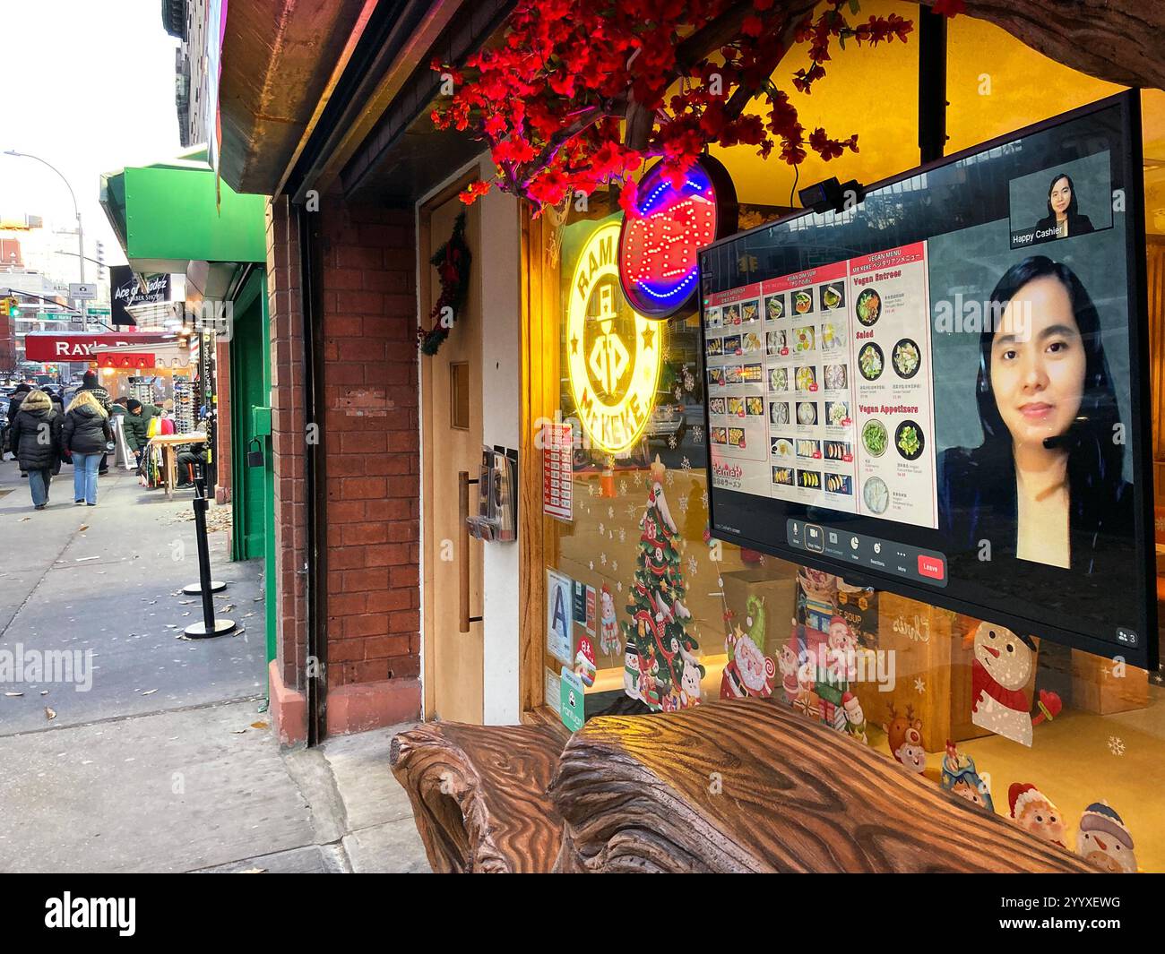 22. Dezember 2024, New York City, New York, USA: Remote AI Kassierer bearbeitet Restaurantbestellungen. Im RAMEN Mr. Keke Restaurant werden die Bestellungen zunächst von einem entfernten KI-Kassierer auf einem Bildschirm hinter dem Frontfenster entgegengenommen, der die Zahlung für alles übernimmt, was man essen kann. Cooper Square und 7th Street. New York City. (Kreditbild: © Billy Tompkins/ZUMA Press Wire) NUR REDAKTIONELLE VERWENDUNG! Nicht für kommerzielle ZWECKE! Stockfoto