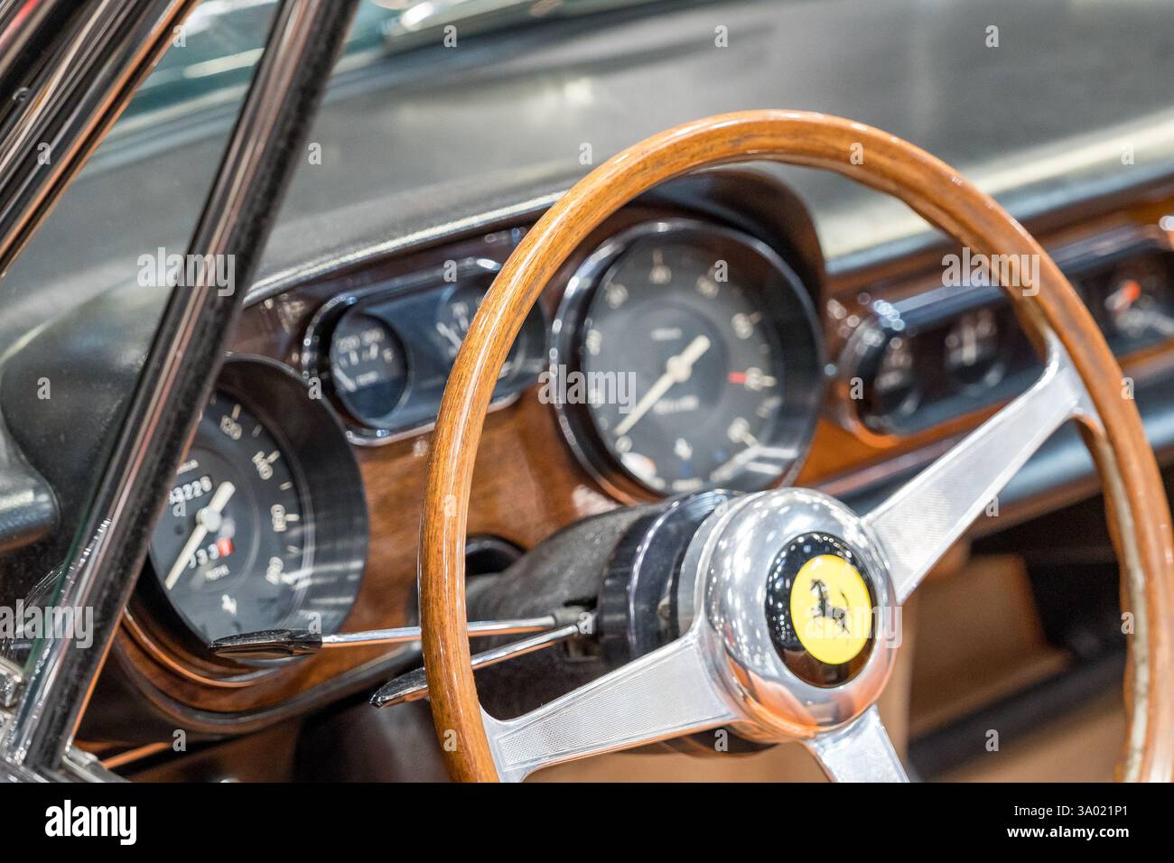 Der Innenraum eines klassischen Luxusautos zeigt poliertes Holz und ein ikonisches Emblem, das den Charme der klassischen Automobilwerkskunst in einem Rahmen einfängt Stockfoto