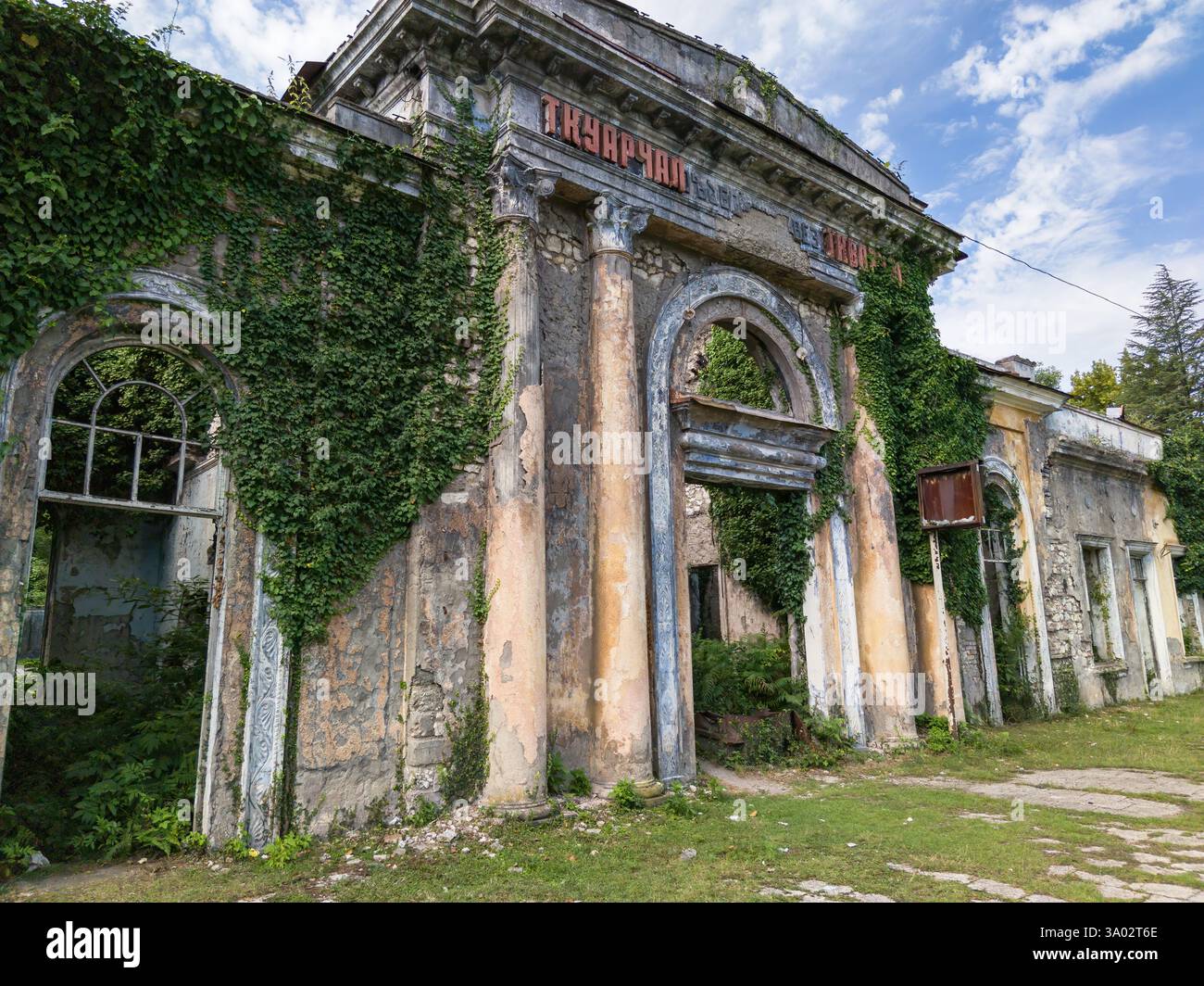 Verlassener Bahnhof in der Stadt Tkvarcheli, Abchasien. Alte Bauruinen, die im Sommer von Gras und Efeu bewachsen sind. Konzept von Krieg, Grunge, Architektur. Stockfoto