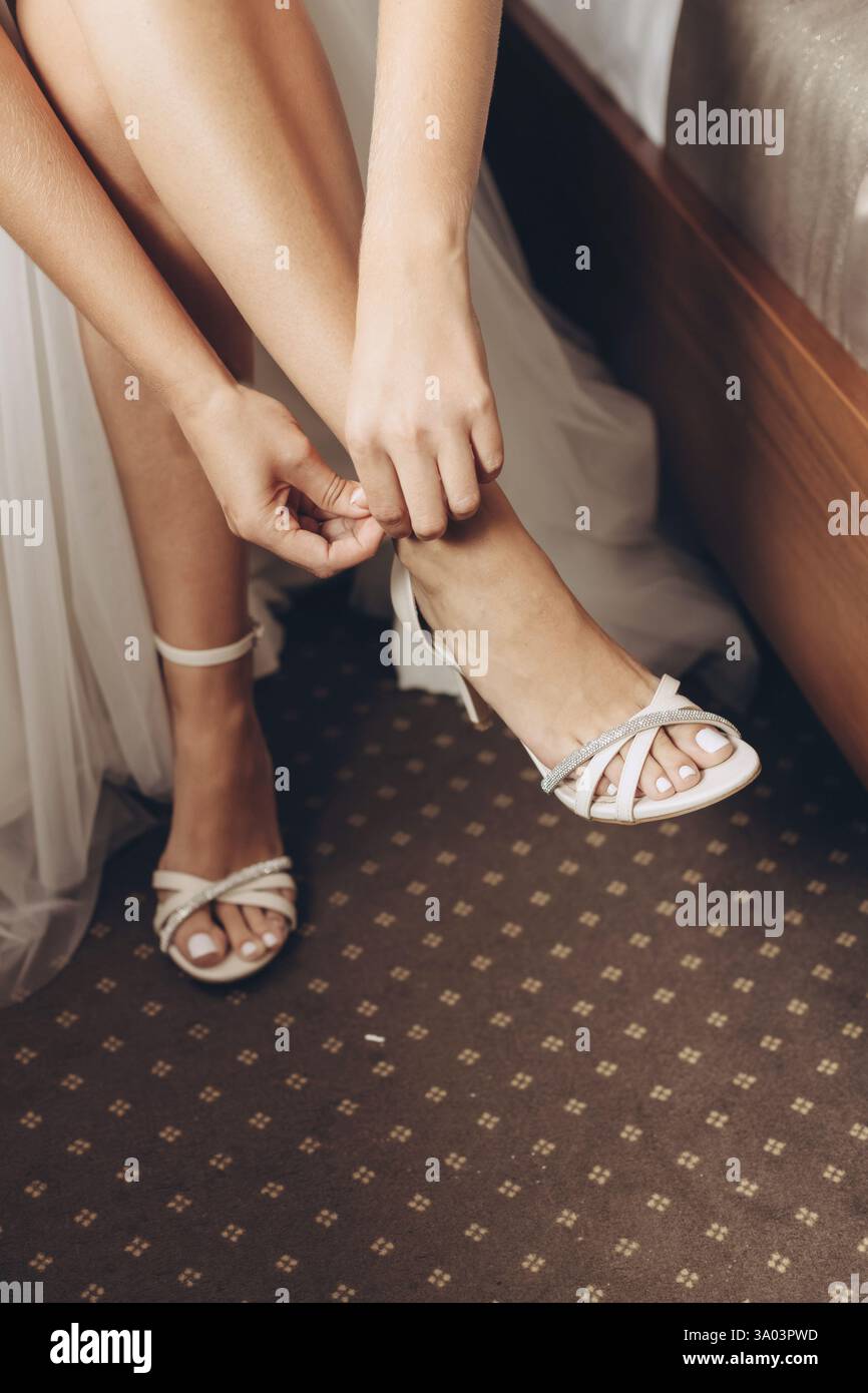 Braut zieht leichte Hochzeitsschuhe an Stockfoto