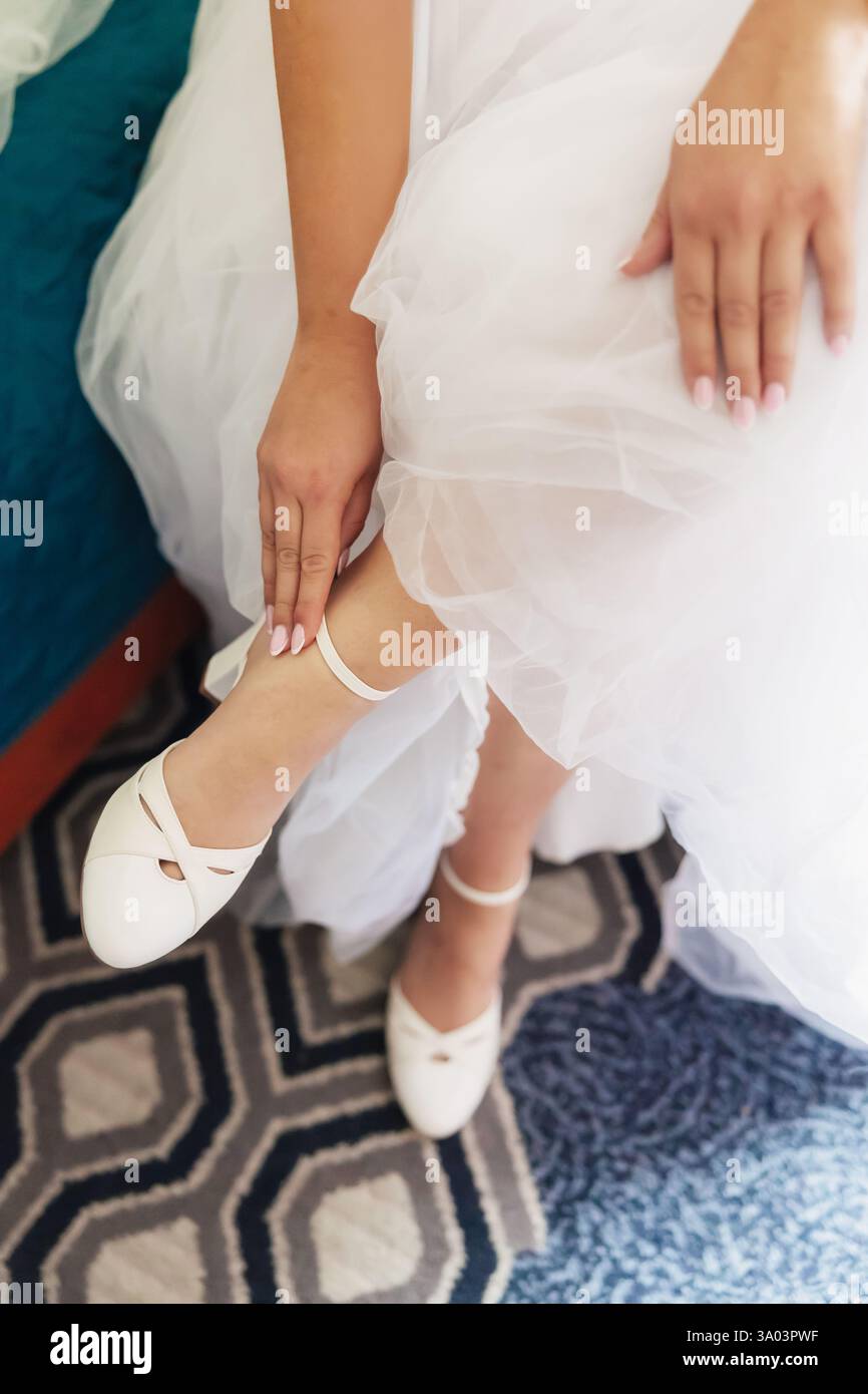 Braut zieht leichte Hochzeitsschuhe an Stockfoto