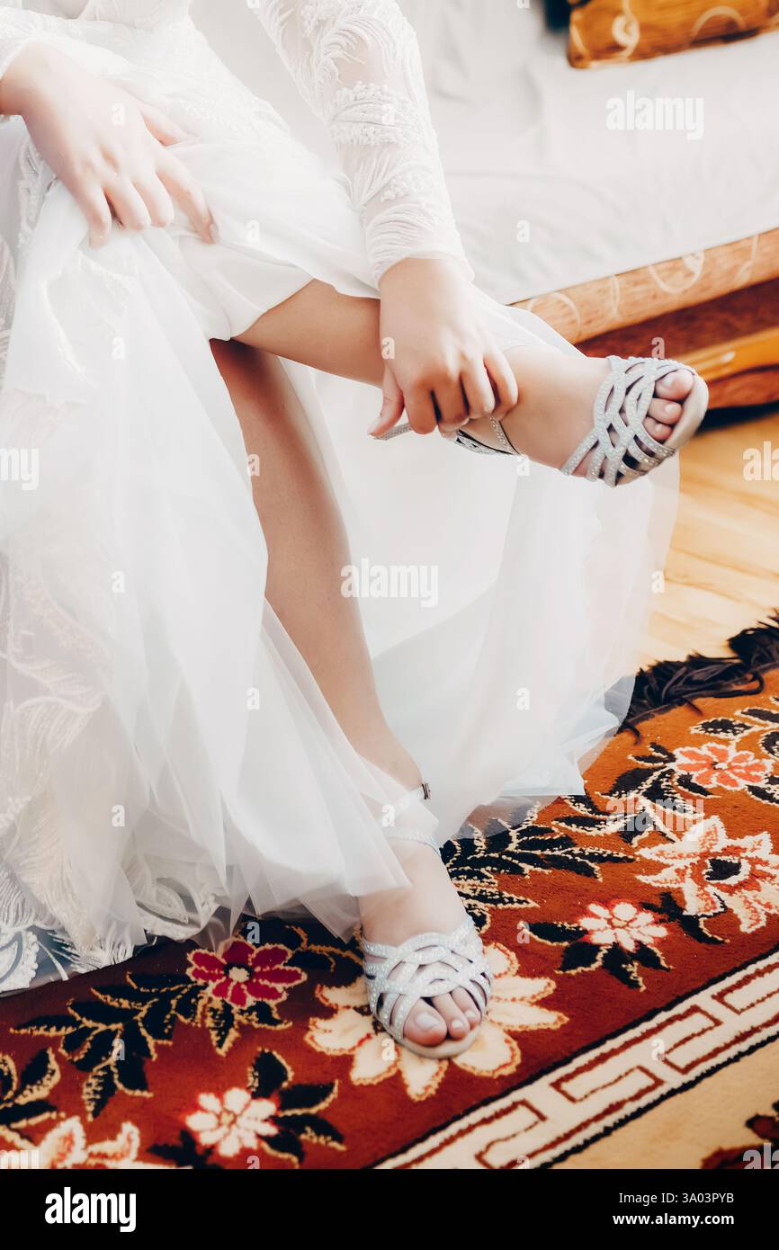 Braut zieht leichte Hochzeitsschuhe an Stockfoto