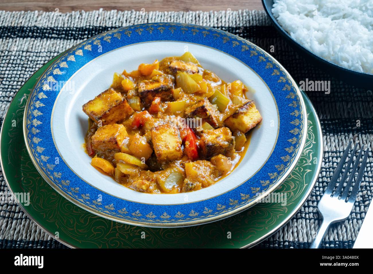 UK. Eine frisch gekochte Schüssel Paneer Balti Curry serviert auf einem Tisch mit Reis. Eine traditionelle indische Mahlzeit mit gebratenem Paneer-Weichkäse Stockfoto