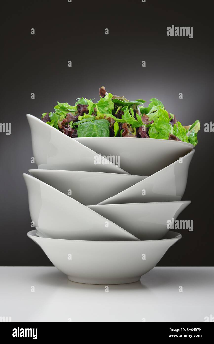 Ein grüner Salat in der oberen Schüssel eines Stapels weißer porzellanschüsseln. Stockfoto