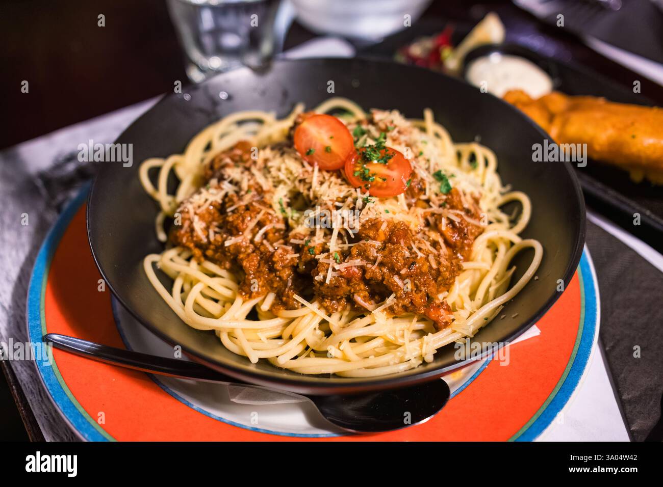 Spaghetti mit Hackfleischsoße und Käse auf schwarzer Platte im italienischen Restaurant Stockfoto