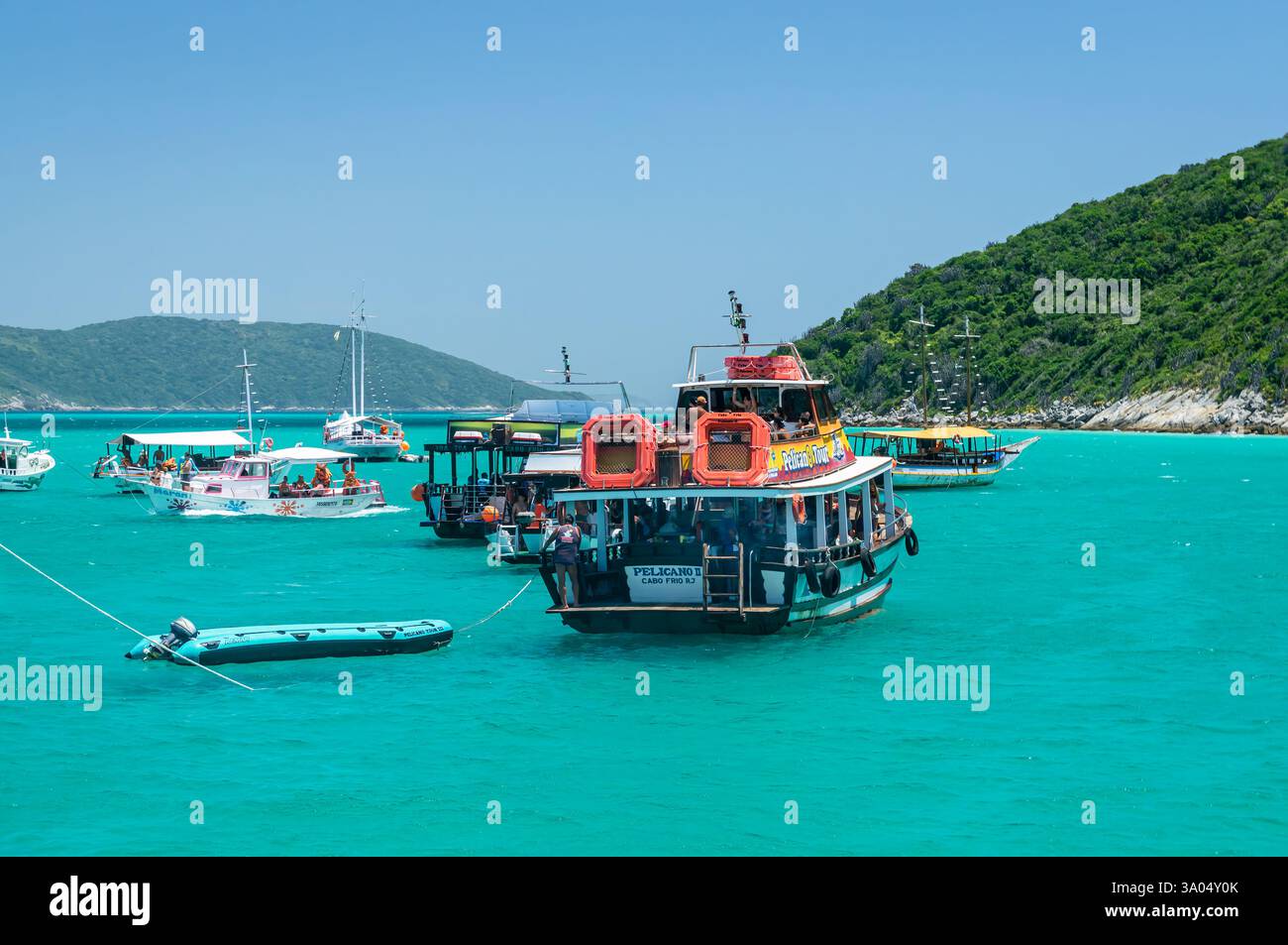 Viele Schoner und Schlauchboote ankerten in der Bucht von Guriri in türkisfarbenem Wasser in der Nähe der Insel Ilha do Farol unter dem klaren blauen Sommermorgenhimmel. Stockfoto