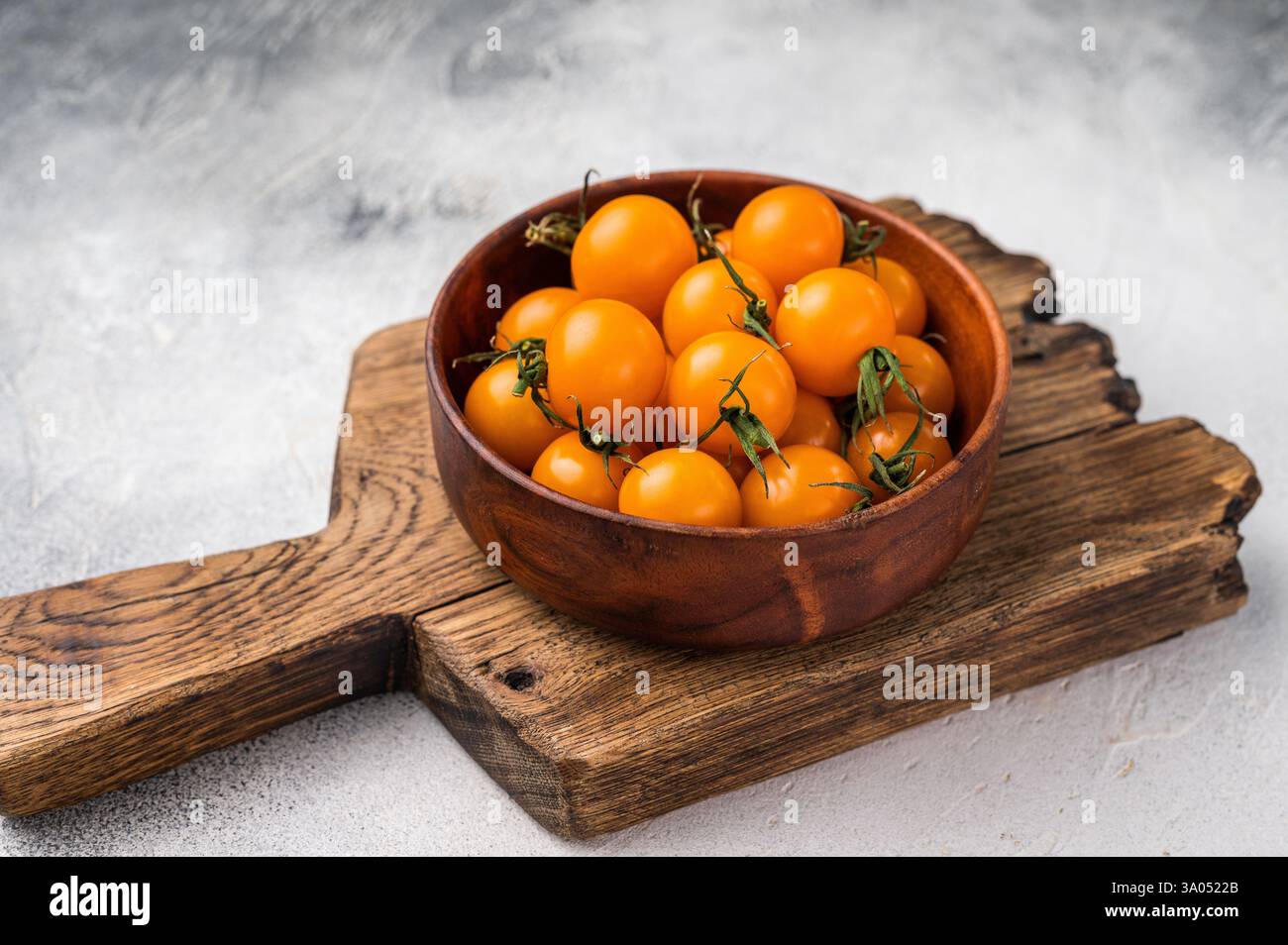 Frische kleine gelbe Kirschtomaten-Sortiment, Mini-Bio-Cocktail-Tomatenmischung. Grauer Hintergrund. Draufsicht. Stockfoto
