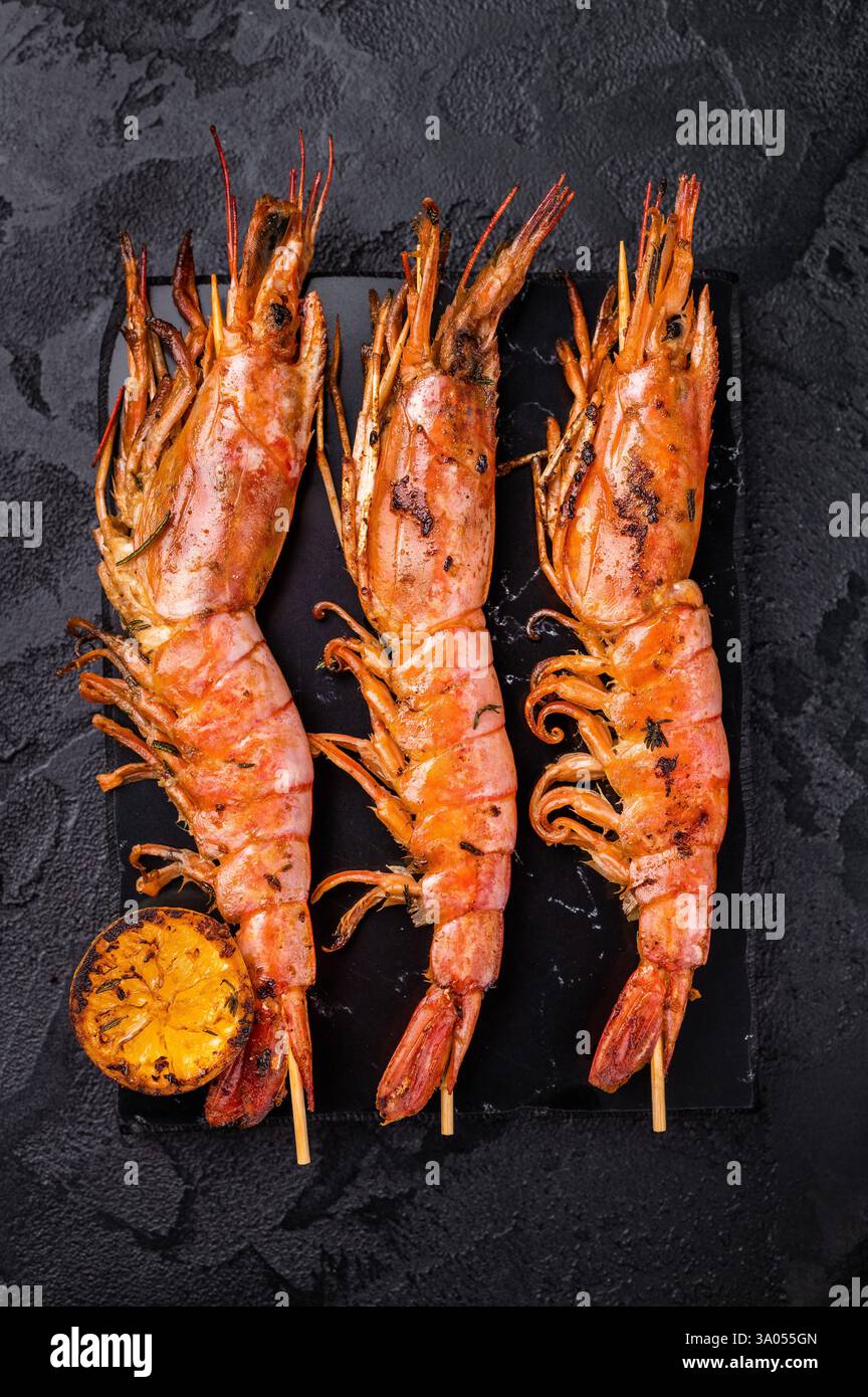 Garnelenkebab, Spieße mit gegrillten roten Garnelen Langostino Austral. Schwarzer Hintergrund. Draufsicht. Stockfoto