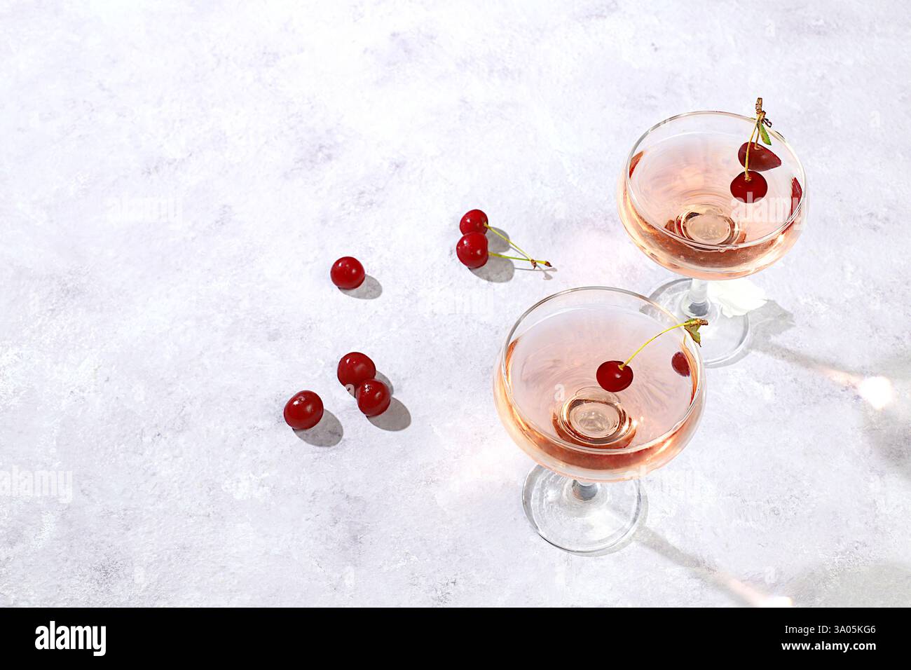Modernes Stillleben mit Rosenwein, alkoholischem Cocktail und Kirschbeeren auf elegantem modernem Hintergrund, minimales Konzept für Bar und Feiertagsparty, Café, Stockfoto