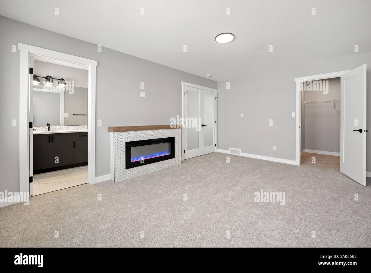 Großes, leeres Zimmer mit Kamin und begehbarem Schrank. Das Zimmer ist sehr sauber und gut beleuchtet, was ihm eine gemütliche und einladende Atmosphäre verleiht Stockfoto