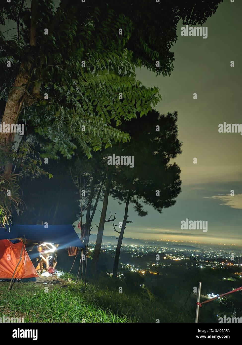 Ein ruhiger Campingplatz bei Nacht mit atemberaubendem Blick auf die Lichter der Stadt von einem hohen Aussichtspunkt. Der perfekte Ort für Outdoor-Enthusiasten und Reisen Stockfoto