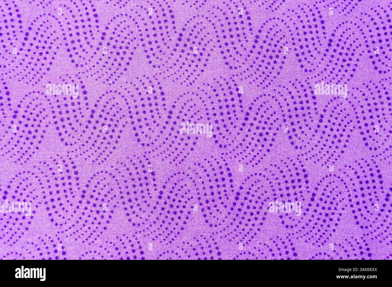 Nahaufnahme von Wellen blauer, kaskadierender Punkte auf hellviolettem Stoff, flach auf weißem Hintergrund. Stockfoto