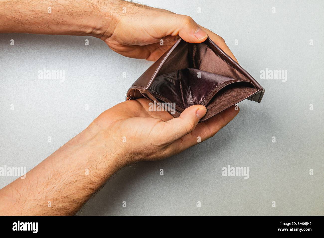 Zwei Hände halten eine offene, leere Geldbörse und symbolisieren finanzielle Not und Sorgen um Ausgaben in einer Zeit wirtschaftlicher Unsicherheit und des Arbeitsplatzverlusts. Stockfoto