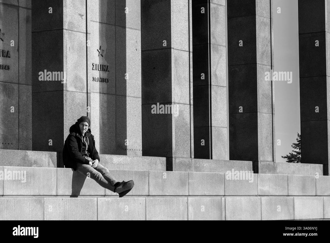 Ein einsamer junger Mann, der sich an einem sonnigen Tag neben dem Slavín-Denkmal erholt. Bratislava, Slowakei. Stockfoto