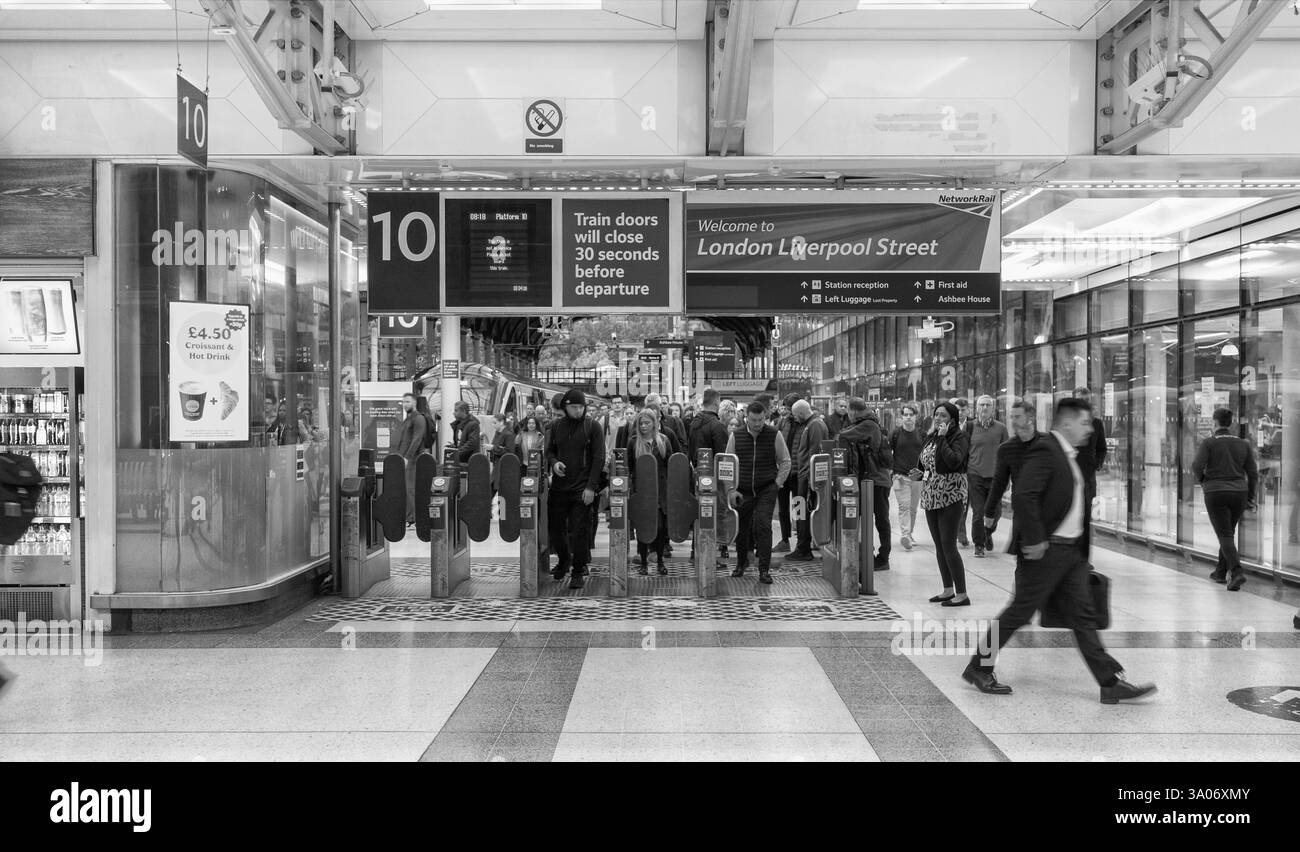 Pendler/Passagiere, die während der morgendlichen Hauptverkehrszeit die automatischen Fahrkartenschranken am Bahnhof London Liverpool Street passieren Stockfoto
