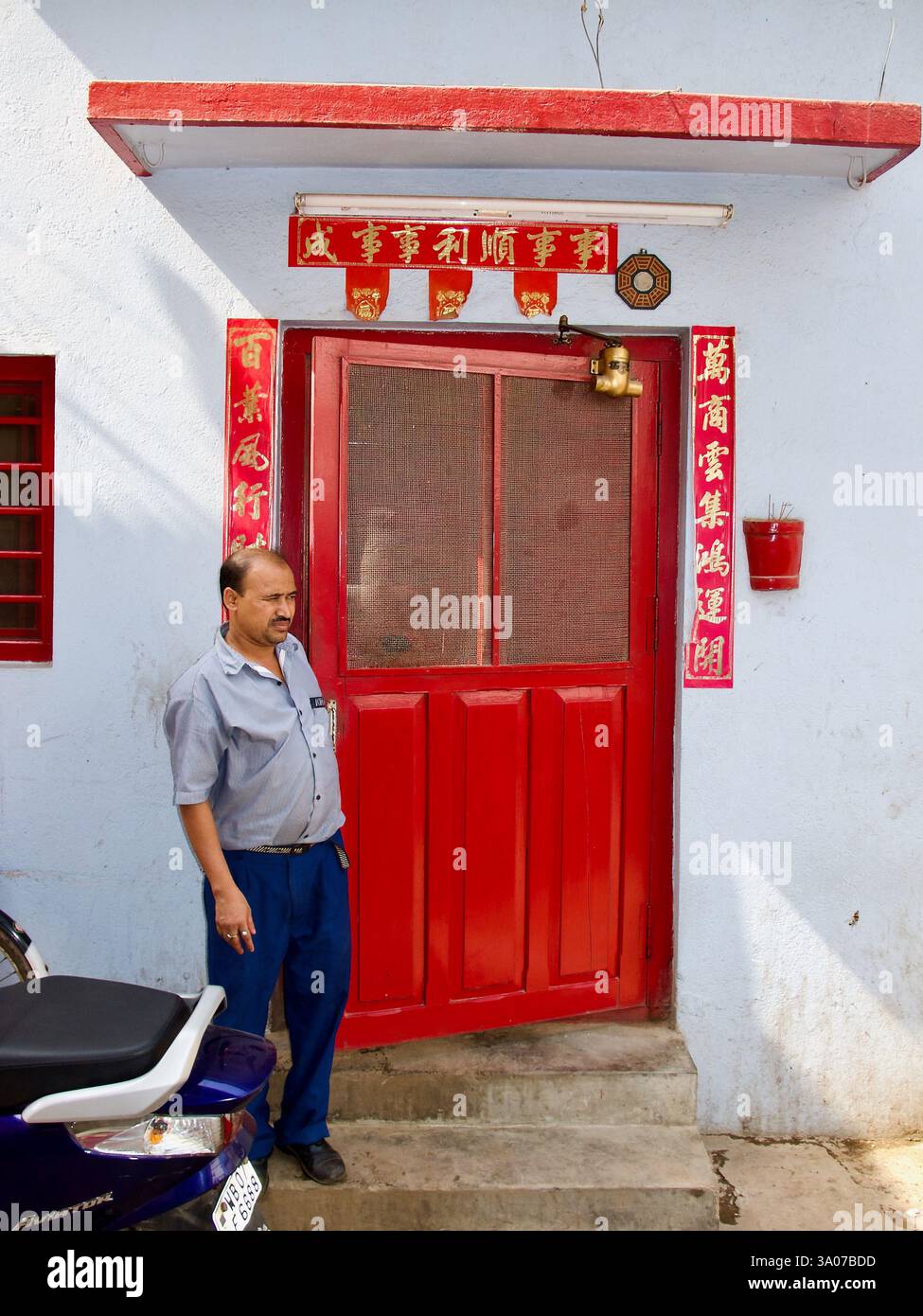 Ein Mann steht vor einem chinesischen Haus mit roten Dekorationen und verheißungsvollen Botschaften in Tangra, Kalkutta, wo sich eine historische chinesische Gemeinde befindet Stockfoto