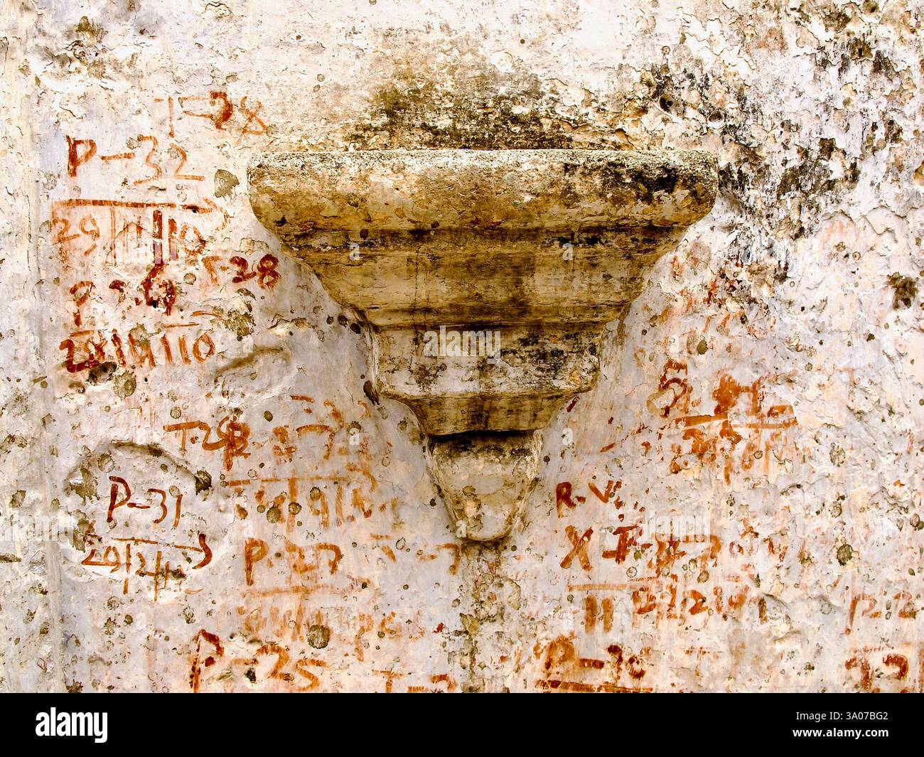Verwitterte Wanddetails in Bakraur, in der Nähe von Bodh Gaya, Bihar, Indien, mit einer alten Alkove mit roten numerischen Inschriften. Stockfoto