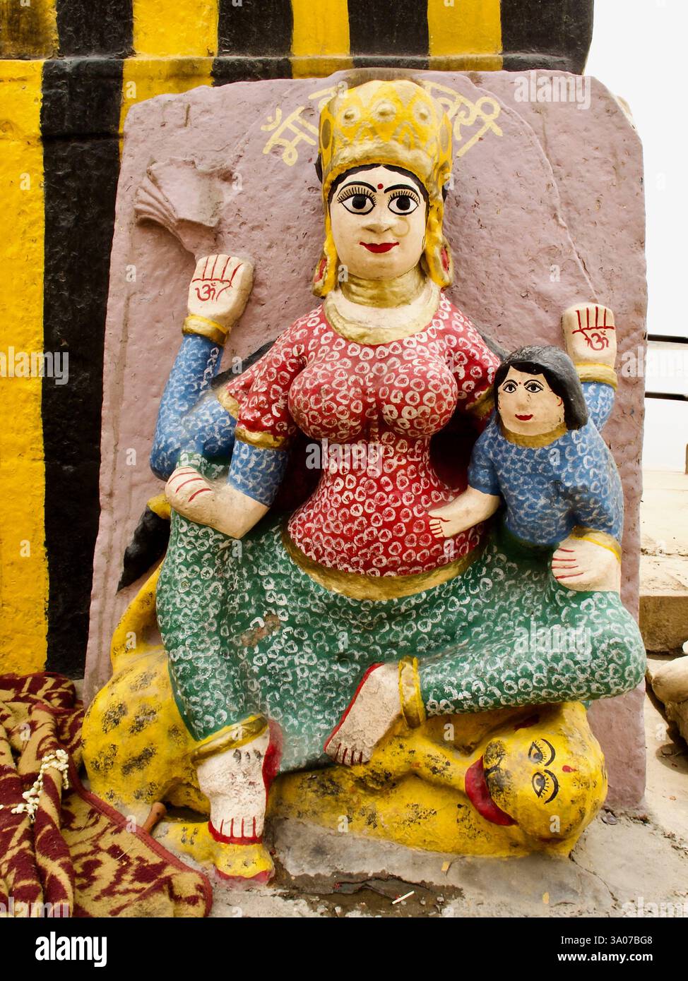 Volksidol von Skandamata in einem Schrein in Ramnagor, Varanasi, das die Göttin darstellt, die mit ihrem Kind auf einem Löwen sitzt und die göttliche Mutterschaft symbolisiert. Stockfoto