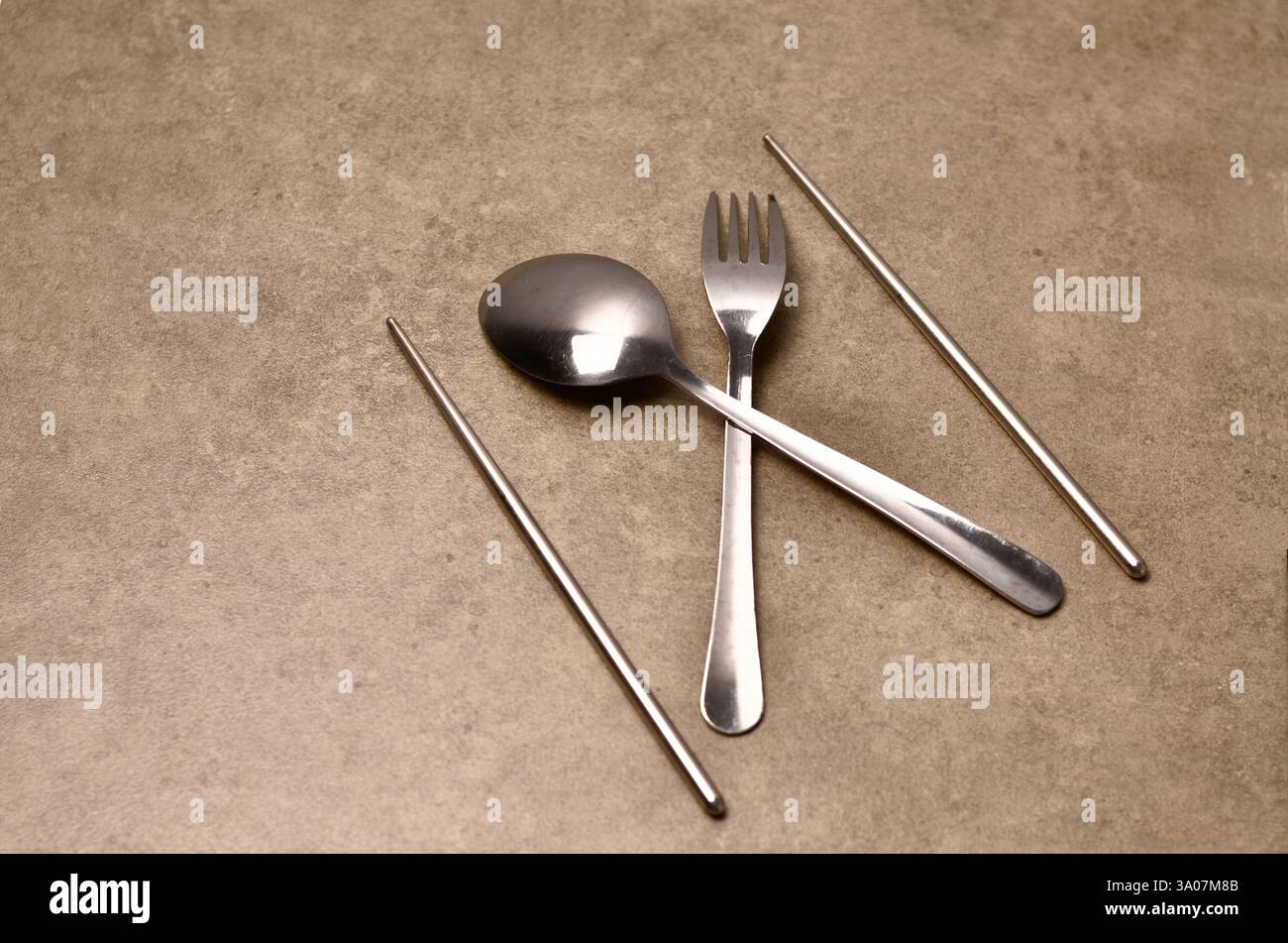 Metallgeräte, einschließlich Gabel, Löffel und Essstäbchen auf rustikaler Oberfläche Stockfoto