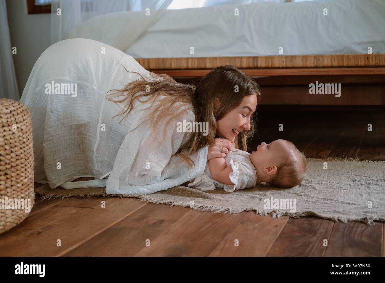 Ein Baby liegt auf der Decke und lacht, Mama spielt mit ihr. Kitzelt Tochter. Stockfoto