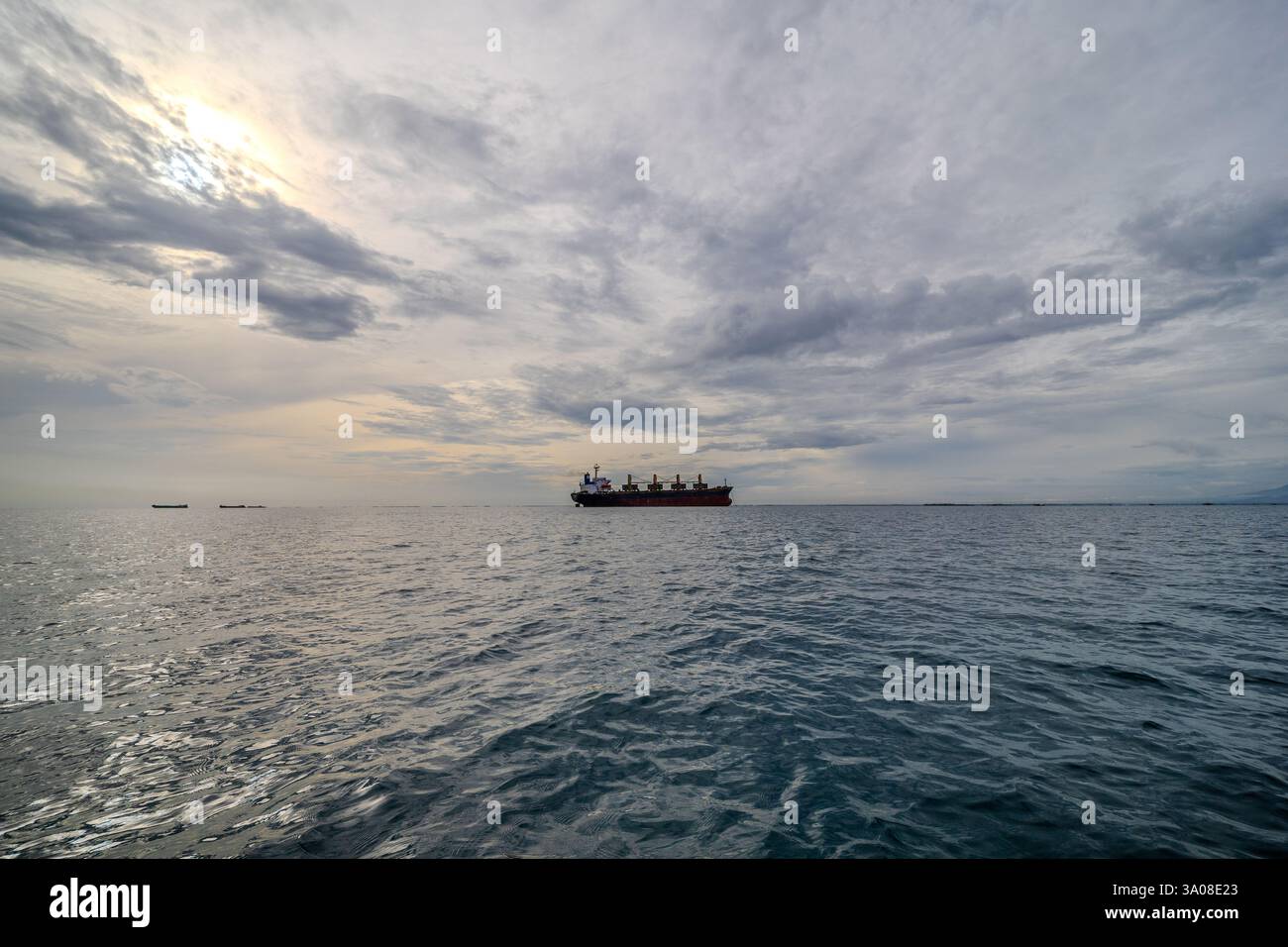 Offshore-Frachtschiff schwimmt auf ruhigen Gewässern des Ozeans. Dramatischer Himmel und Meer am Morgen Stockfoto Offshore-Frachtschiff schwimmt auf ruhigen Gewässern des Ozeans. Dramatischer Himmel und Meer am Morgen Stockfoto