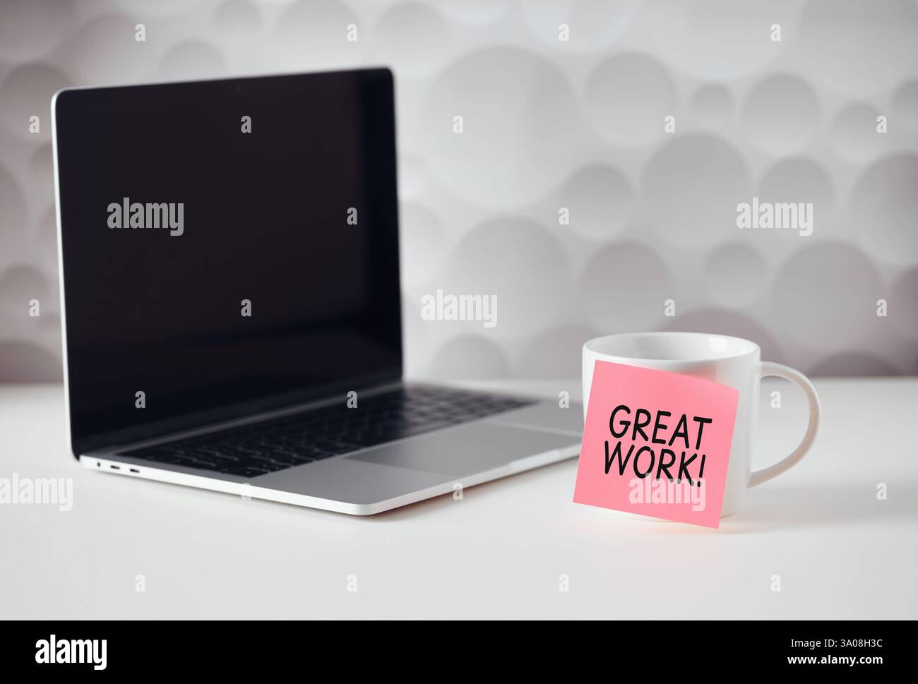 Rosafarbene Haftnotiz mit großartiger Arbeitsbotschaft, die den Mitarbeiter am Arbeitsplatz motiviert, moderner Laptop mit leerem Bildschirm neben Kaffeetasse auf weißem Tisch Stockfoto