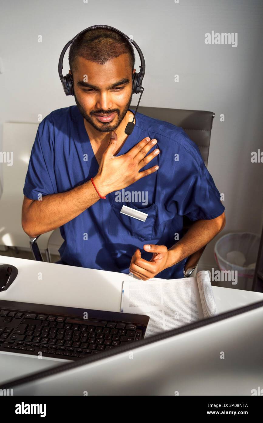 Hochwinkelansicht des männlichen Gesundheitsexperten, der Anweisungen während der Online-Konsultation durch Videoanruf in der Klinik gibt Stockfoto