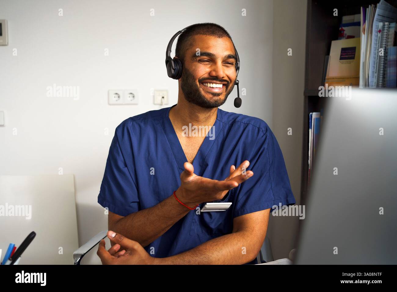 Glücklicher männlicher medizinischer Fachmann, der ein Headset trägt, das Patienten durch Videoanruf in der Klinik im Krankenhaus unterstützt Stockfoto