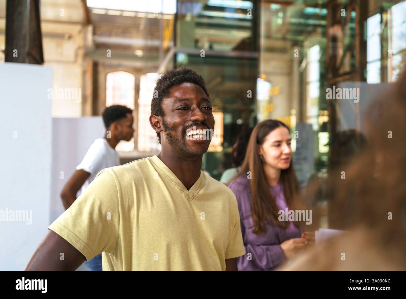 Fröhlicher männlicher Student, der auf dem College-Campus steht Stockfoto