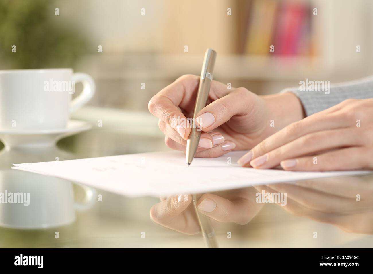 Nahaufnahme einer Frau, die einen Vertrag auf einem durchsichtigen Schreibtisch zu Hause unterzeichnet Stockfoto