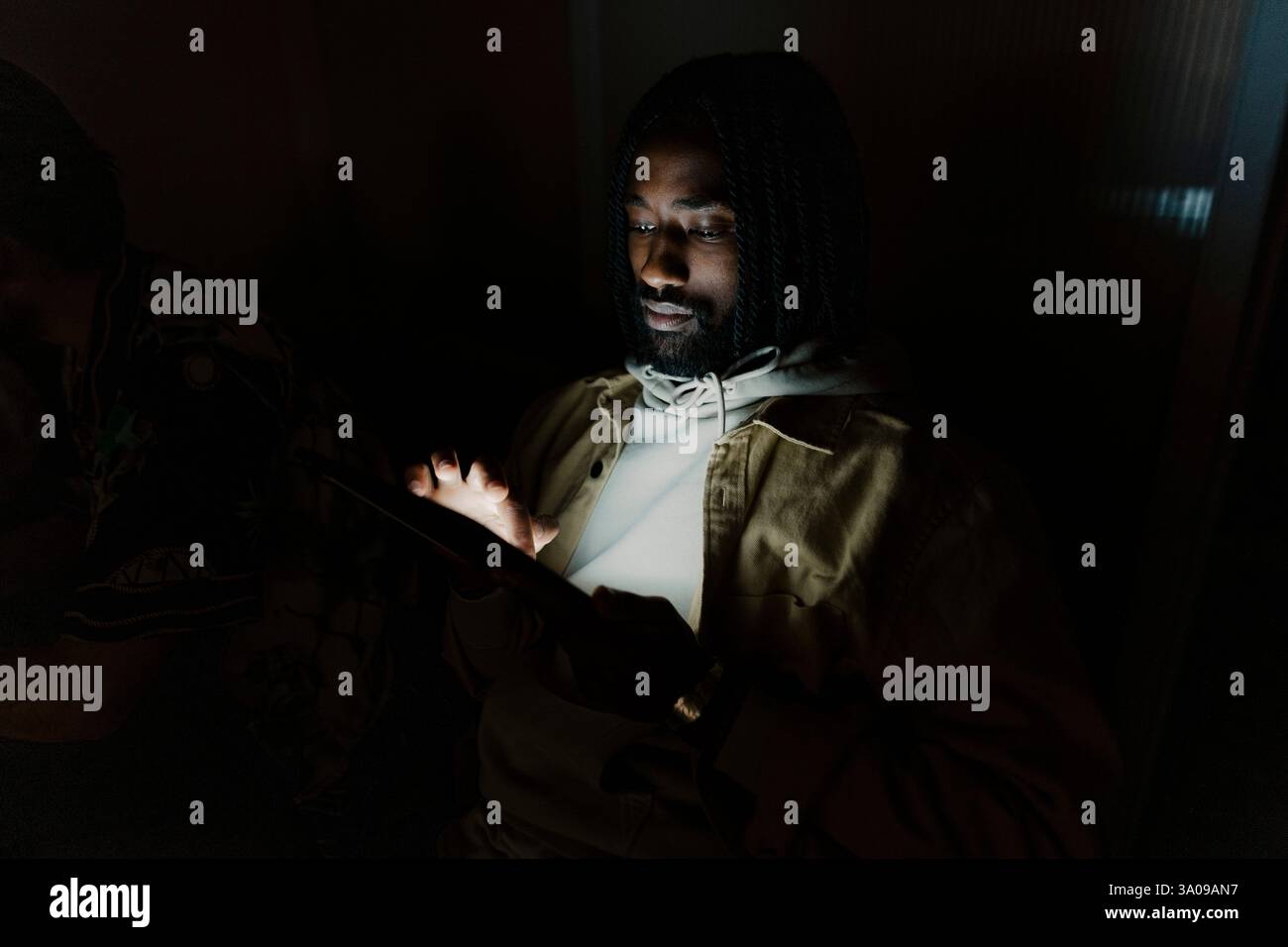 Junger Geschäftsmann, der im Dunkeln über einen Tablet-PC im Internet surft Stockfoto