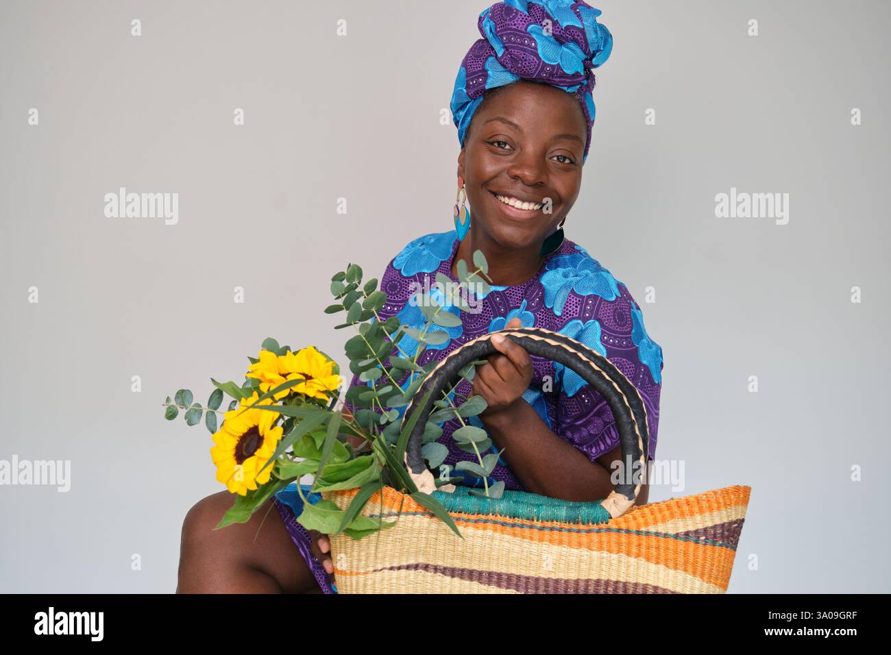 Frau mit Sonnenblumen und Eukalyptusstrauß in einer bunten Tasche Stockfoto