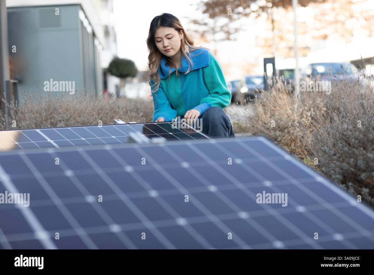 Eine junge Frau, die eine Photovoltaikanlage in der Stadt überprüft Stockfoto