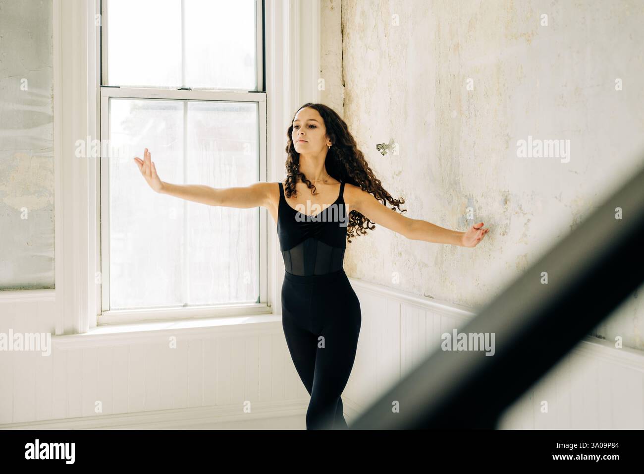 Die Balletttänzerin bewegt sich anmutig, die Arme gestreckt, in einem Vintage-Studio Stockfoto