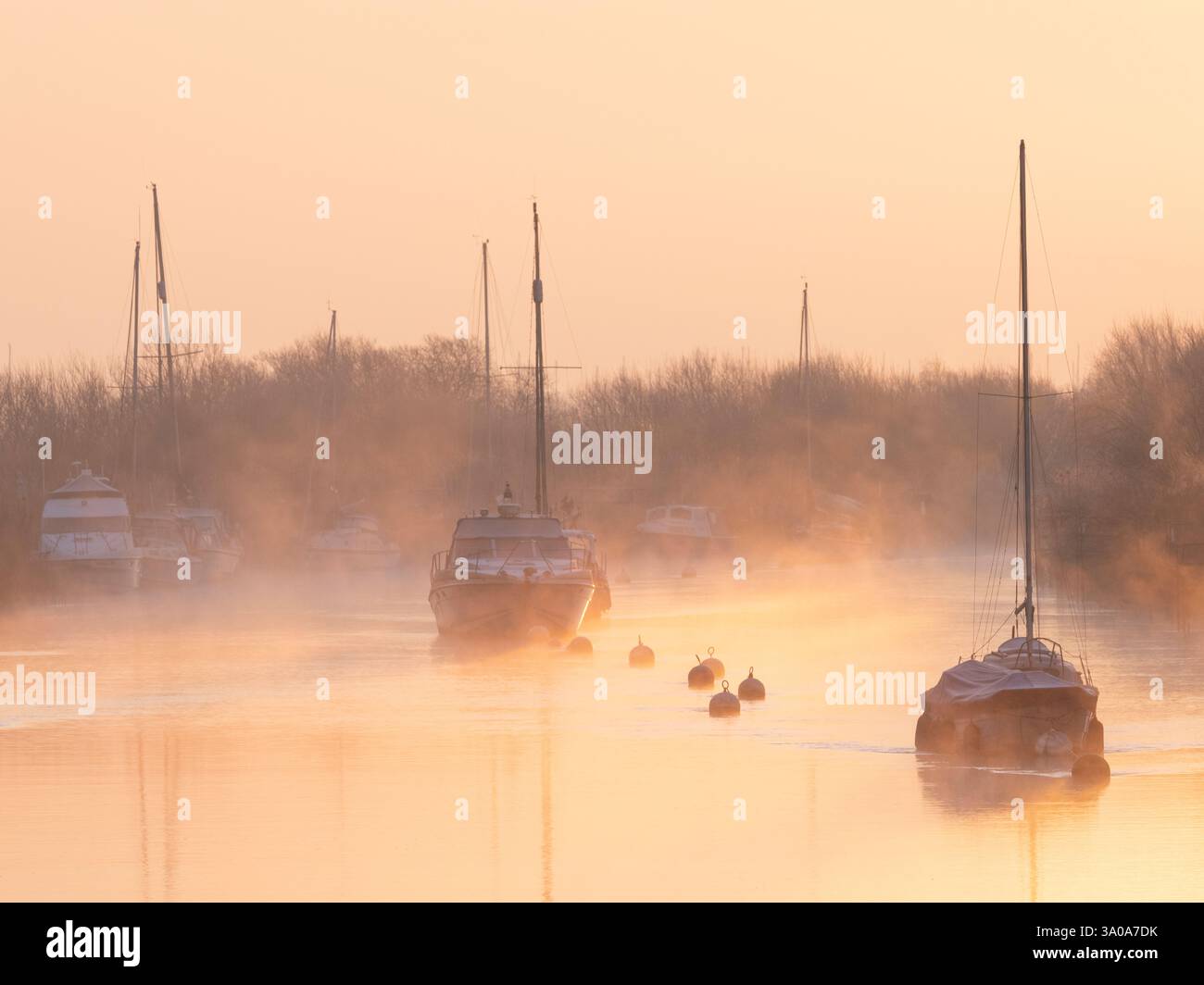 River Frome, Wareham, Dorset, Großbritannien. März 2025. Wetter in Großbritannien: Boote, die am Frome ankern, sind bei Sonnenaufgang zu Beginn eines weiteren schönen Frühlingstages in weichem Nebel gehüllt. Das herrliche Frühlingswetter wird sich bis weit in die Woche fortsetzen. Quelle: Celia McMahon/Alamy Live News Stockfoto